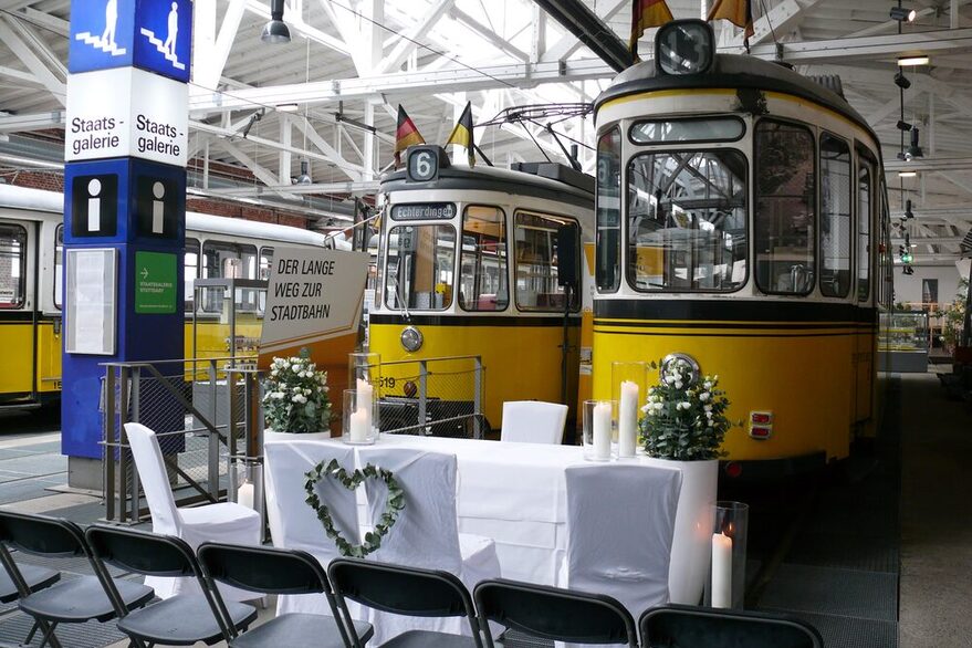 Hochzeitsdekoration, Stühle und Tisch vor historischen Straßenbahnen.