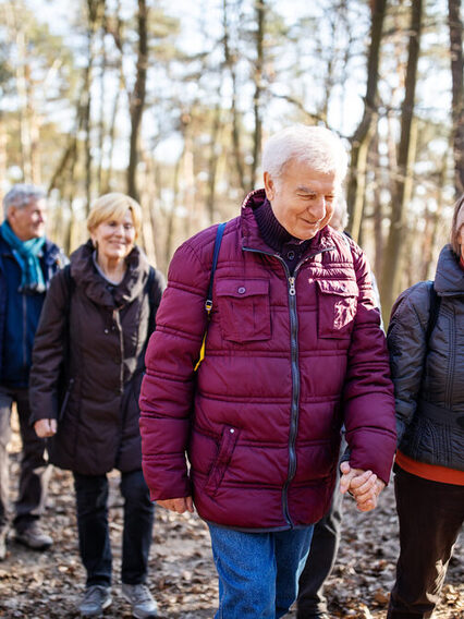 Ältere Menschen wandern durch den Wald.