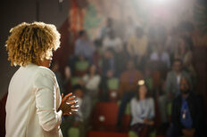 Rear view of the conference speaker giving talk at conference event.