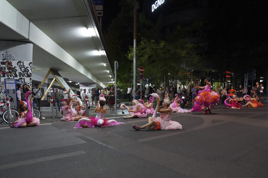 Als rosafarbene Flamingos verkleidete Personen bei Nacht auf einem beleuchteten Platz in Stuttgart.