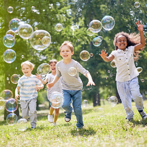 Children in the park run after the soap bubbles.