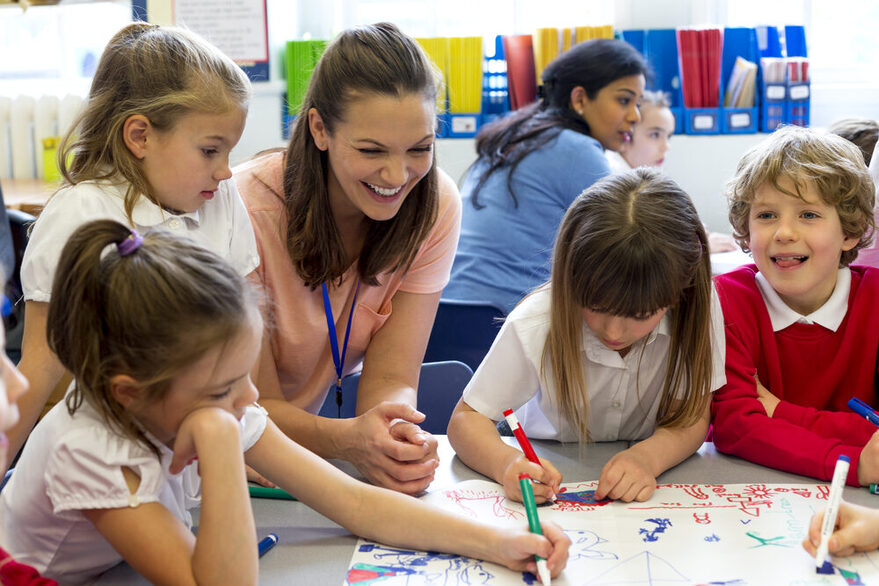 Einige Kinder malen gemeinsam an einem Tisch an einem großen Bild.