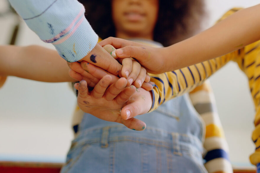 Motivation, friends hands together and support in a classroom of their school building. Partnership or team building, learning or education and people stack their hand for teamwork or collaboration