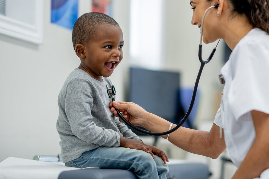 A child is examined by a pediatrician with a stethoscope on her chest.