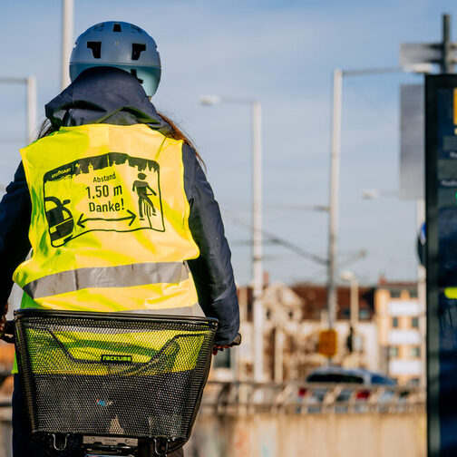 Radfahrerin in Warnweste fährt an einer Zählstation vorbei.