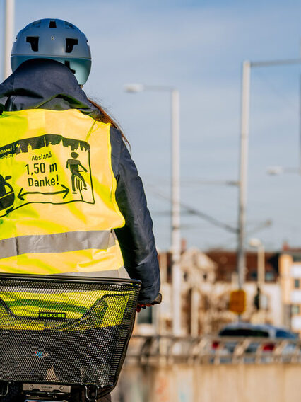 Radfahrerin in Warnweste fährt an einer Zählstation vorbei.