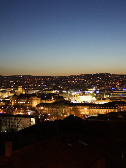 Blick auf eine beleuchtete Stadt kurz nach Sonnenuntergang.