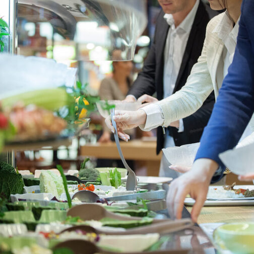 In einer Kantine: Menschen bedienen sich an einem Salat-Buffet.