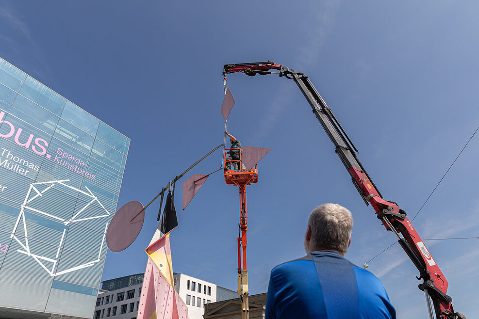 Roter Kran stellt vor dem Kunstmuseum Stuttgart ein Kunstwerk auf.