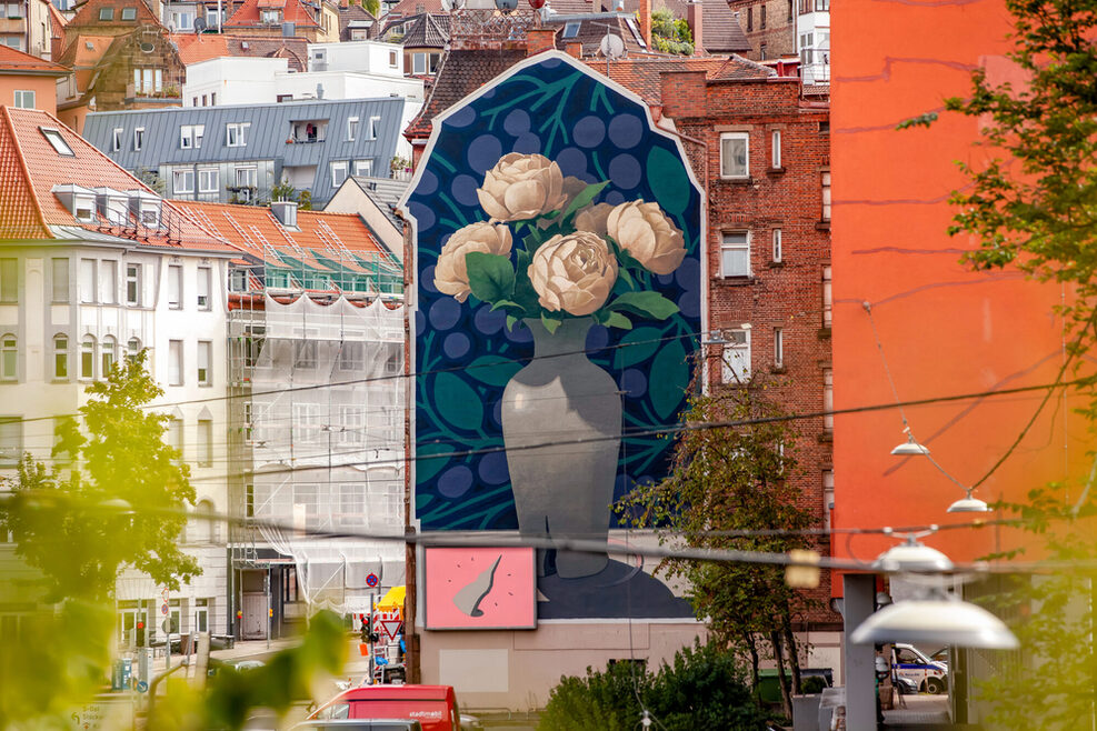 Mural von einer grauen Blumenvase mit weißen Blumen an einer Stuttgarter Hauswand.