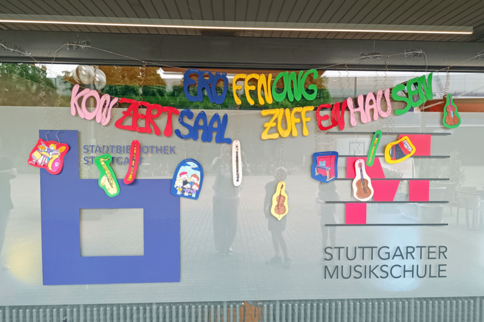 Schaufenster mit dem Logo der Stadtbibliothek und der Musikschule. Vor die Scheibe wurde bunte Buchstaben gehängt die "Eröffnung Konzertsaal Zuffenhausen" schreiben.