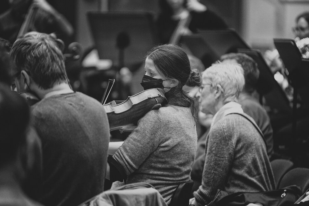 Ein Frau schaut einer Musikerin beim Spielen über die Schulter (Schwarz-weiß Foto).