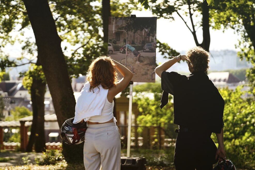 Zwei Personen betrachten ein Bild einer Fotoausstellung im Park.