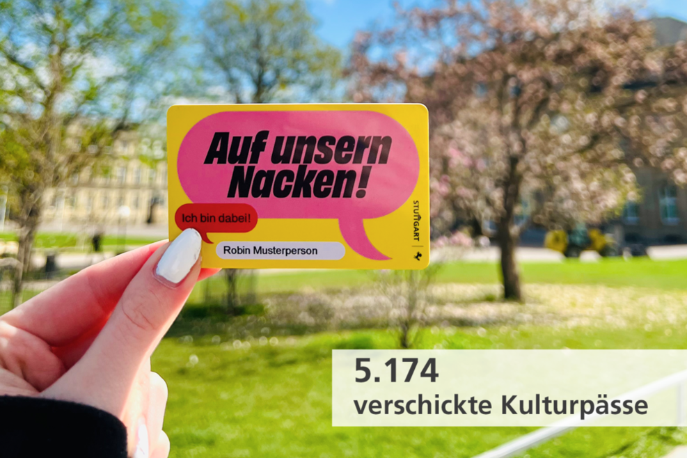 Foto mit Textfeld: Eine Guthabenkarte des Kulturpasses wird vor eine Landschaft gehalten. Auf der Karte sind Sprechblase abgebildet, auf ihnen steht „Auf unsern Nacken!“„Ich bin dabei!“  Textfeld: „5.174 verschickte Kulturpässe“