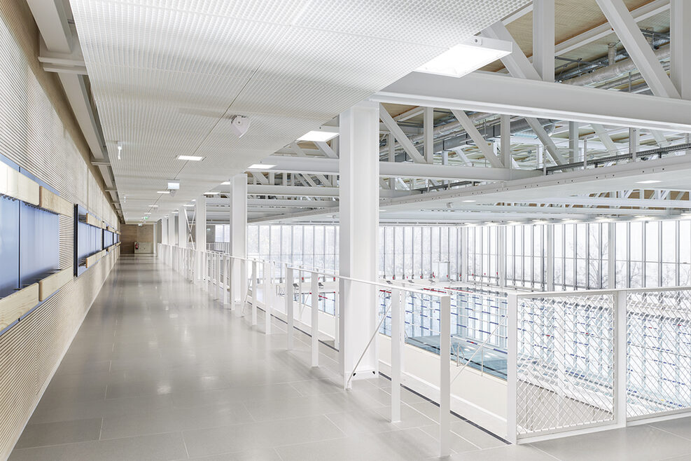 Schwimmhalle Obergeschoss mit Blick über Tribüne und Wettkampfbecken