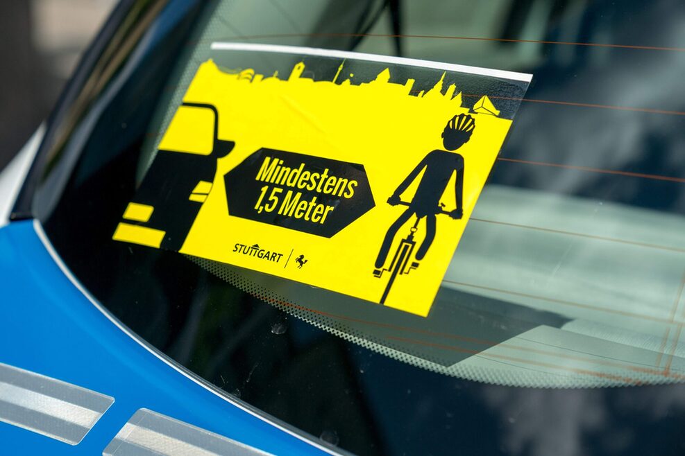 Aufkleber an der Windschutzscheibe: Hier steht "Mindestens 1,5 Meter". Gemeint ist der Abstand zwischen Auto und Radfahrer.