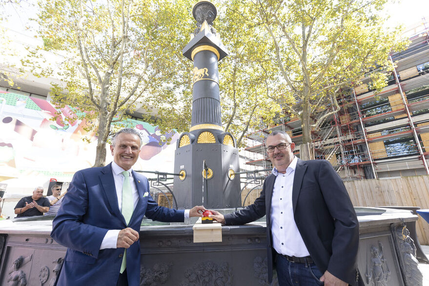 OB Nopper und Jürgen Mutz drücken zur Einweihung des restaurierten Markplatzbrunnen auf einen roten Knopf