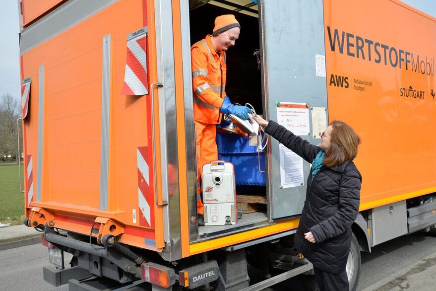 Eien Frau gibt ein Bügeleisen beim Wertstoffmobil ab.