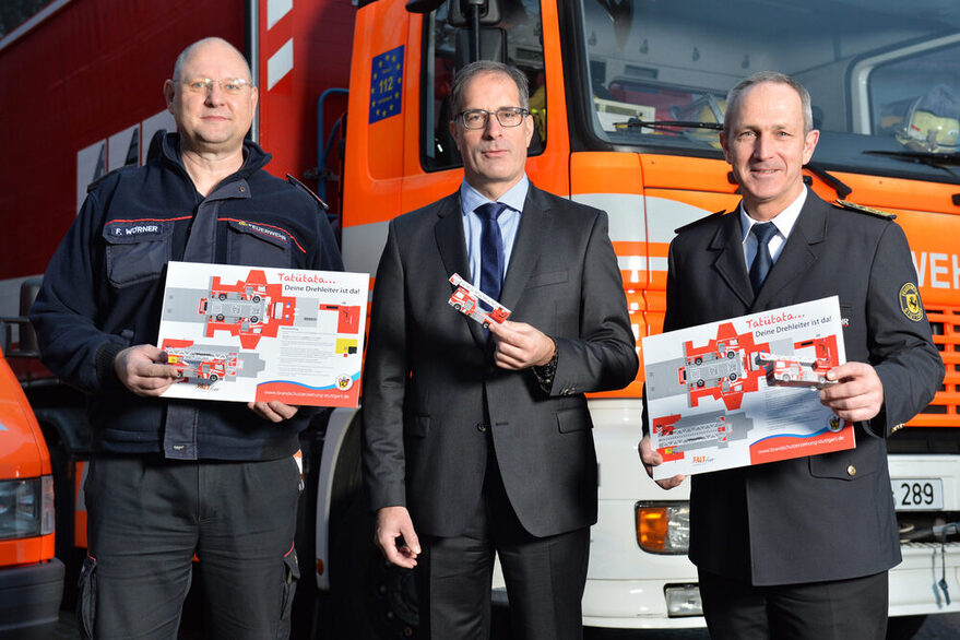 Frank Wörner, Leiter des Arbeitskreises Brandschutzerziehung, mit Clemens Maier, Bürgermeister für Sicherheit, Ordnung und Sport, und Georg Belge, Leiter der Feuerwehr Stuttgart ( v.l.n.r.) bei der Übergabe des neuen Papier-Falt-Bastelbogens.