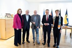 Drei Männer und zwei Frauen stehen nebeneinander in einem Büro.