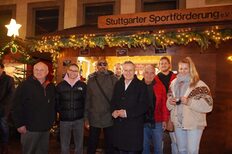 Im Hintergrund ist der Stand der Stuttgarter Sportförderung e.V. auf dem Weihnachtsmarkt zu sehen. Im Vordergrund stehen von Links Präsident der Sportförderung Harald Müller, Schwimmerin Linda Roth, Blindenfußballer Mulgheta Russom, OB Dr. Frank Nopper, Rene Tschur, Sportkreispräsident Fred-Jürgen Stradinger, Patrick Thumm und Volleyballerin Jelena Wlk vor dem Stand der Sportförderung.