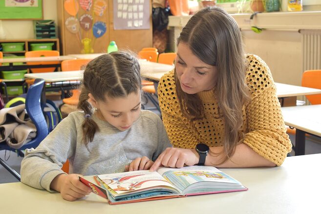 Mentorin Selina Weber und Grundschulkind Lejla Qolli lesen ein Buch.