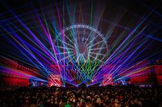 Blick auf den Schlossplatz mit feierndem Publikum, beleutetem Riesenrad und Lasershow.