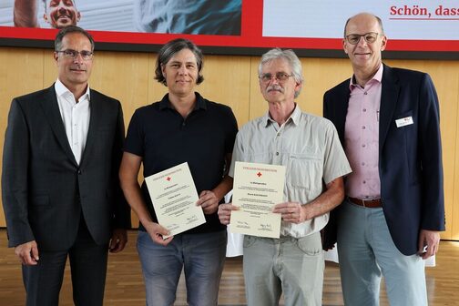 The two long-standing blood donors Tobias Haug and Horst Kaufmann hold a certificate in their hands, next to them stand Mayor Dr. Clemens Maier and the Head of Donor Retention & Recruitment of the DRK Blood Donor Service Baden-Württemberg/Hesse, Dr. med. Michael Müller-Steinhardt.