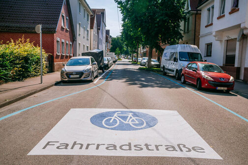 Blick auf die Burgenlandstraße, auf der Straße weist ein großes Fahrad-Symbol auf die Fahrradstraße hin.