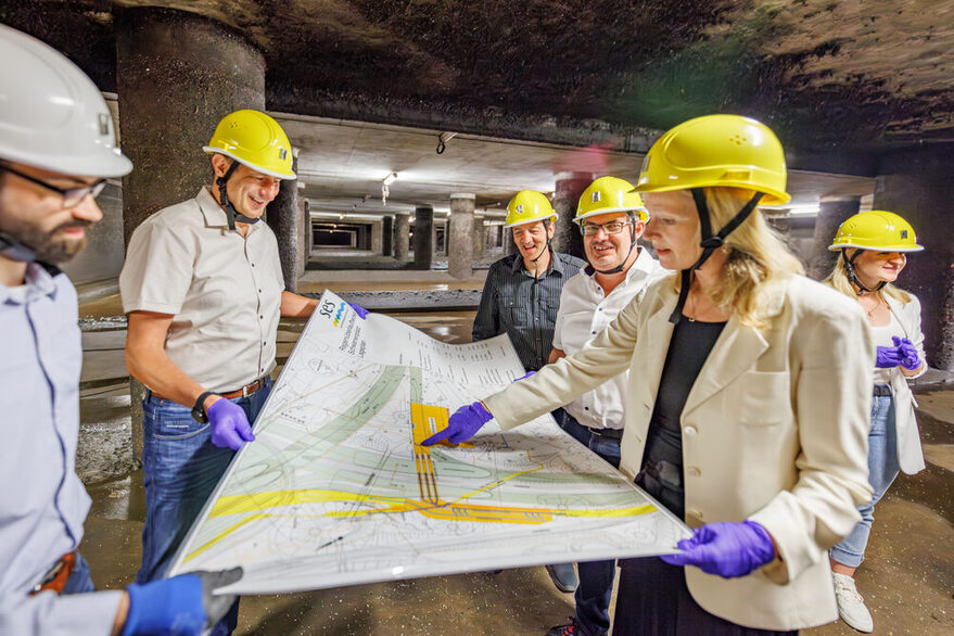 Die Ministerin und Mitarbeiter der Stadtentwässerung schauen auf eine Karte.