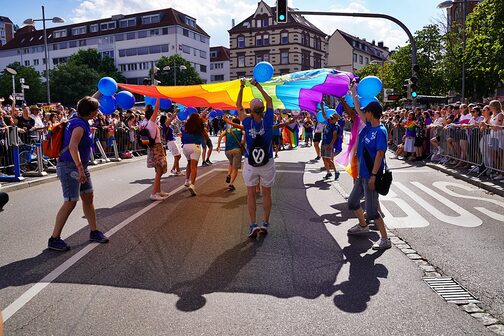 Menschen mit einer großen Regenbogenflagge eim CSD in Stuttgart