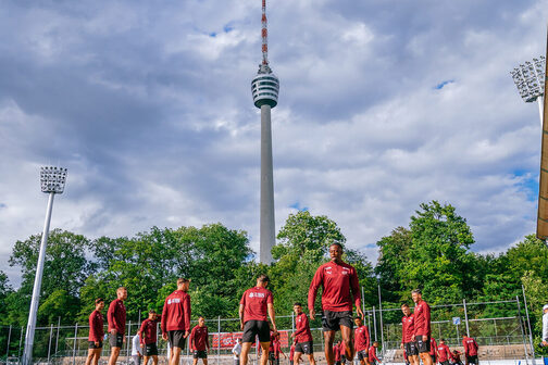 Fußballspieler in roten Trikots stehen auf einem Fußballplatz. Im Hintergrund der Fernsehturm.