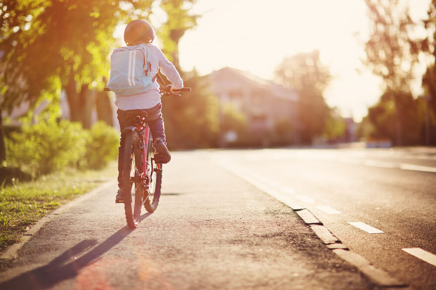 Ein Kind fährt auf einem Fahrrad in den Sonnenuntergang