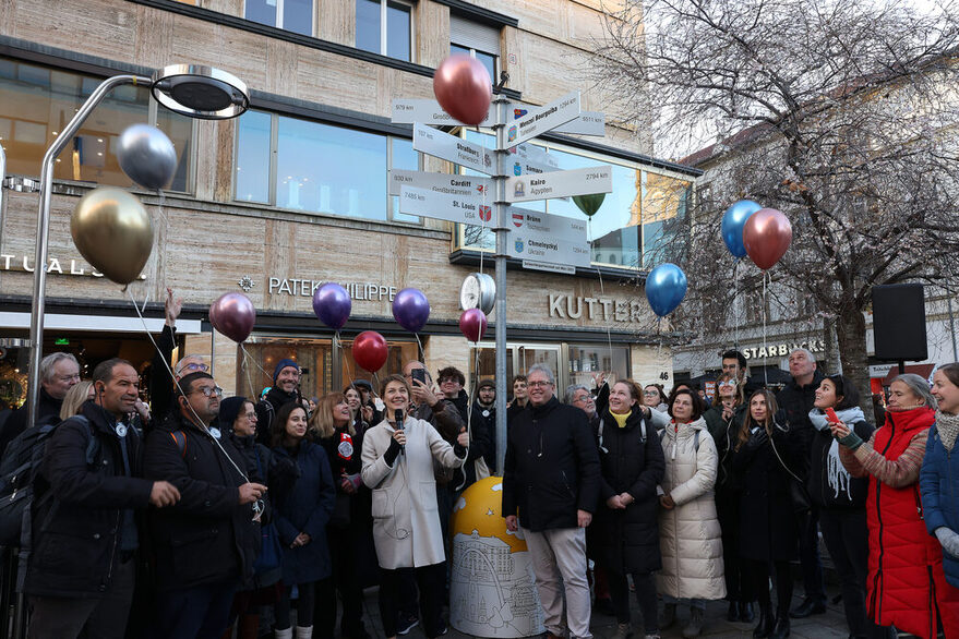 Menschen mit Luftballons vor dem Wegweiser auf der Königsstraße.