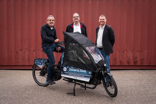 Ralf Maier-Geißer, Head of the Sustainable Mobility Department in Stuttgart, and Stefan Klinkert, Managing Director of Neue Arbeit gGmbH, hand over a cargo bike.rads to a man.