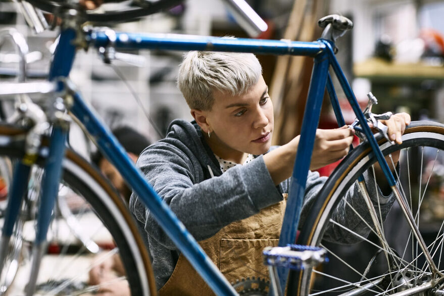 Junge Frau repariert Fahrradbremse