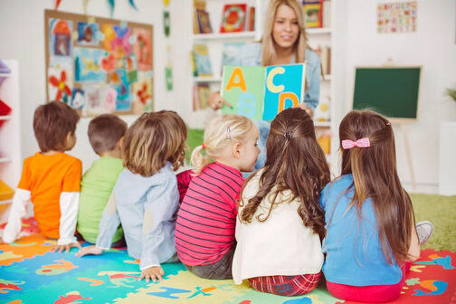 Kinder sitzen vor Erzieherin