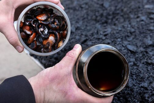 A man holds two filled glasses in his hands.