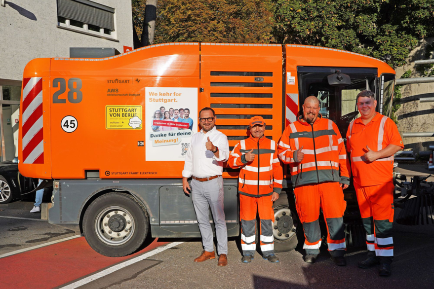 AWS-Geschäftsführer Markus Töpfer mit Mitarbeitern der AWS vor einem Fahrzeug.