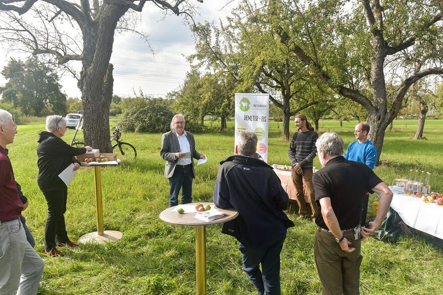 AUf einer Streuostwiese stehen Stehtische und ein Aufsteller. In der Mitte des Bildes stellt der Bürgermeister das neue Konzept vor.