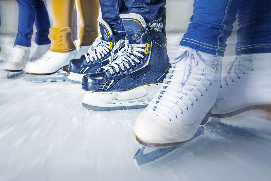 Mehrere Personen mit Schlittschuhe auf einer Eisfläche.