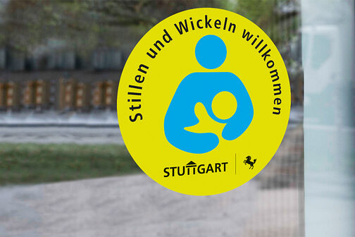 Bild: Sticker, der auf einer Fensterscheibe klebt. Text Sticker: Stillen und Wickeln willkommen. Stuttgart.