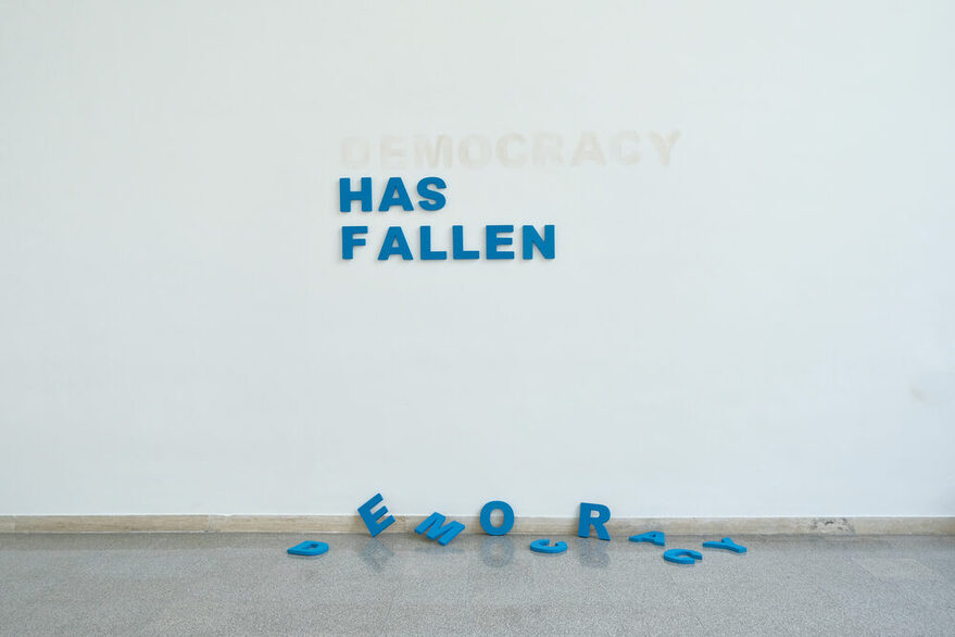 Der Satz "Democracy Has Fallen" steht auf einer Wand, aber die Buchstaben von Democracy liegen auf dem Boden